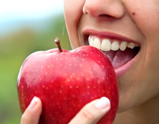 Closeup of patient with dental implants in Pinehurst eating an apple
