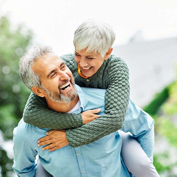 Middle-aged couple smiling after learning how dentures are made in Pinehurst