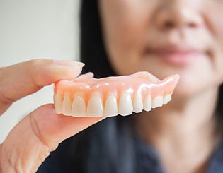 Person holding an upper denture