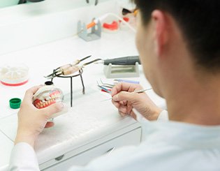 Lab technician altering a denture in the lab