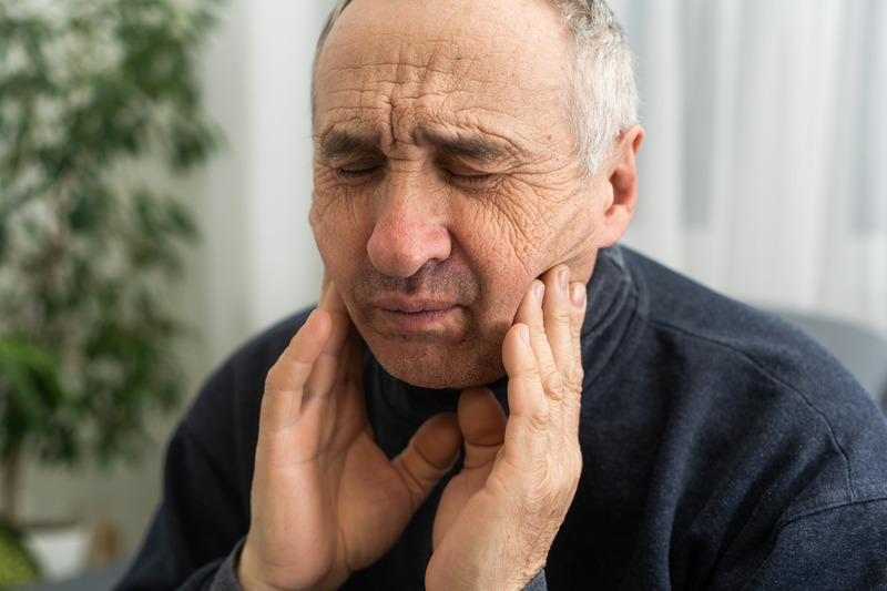 Older patient rubbing gums due to denture sores